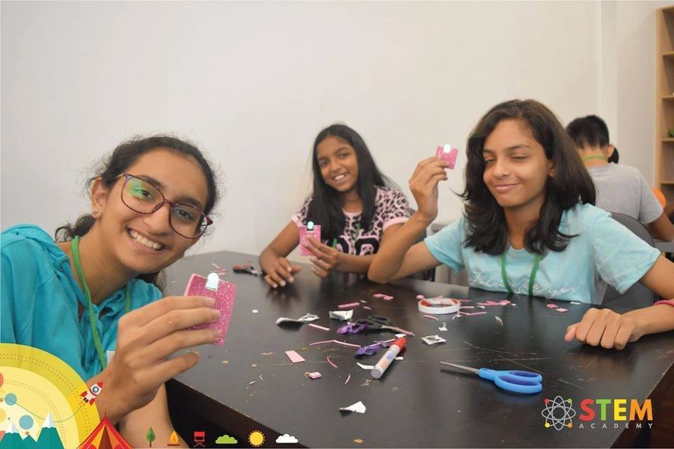 Girls smiling while building a craft project at a STEM Academy camp