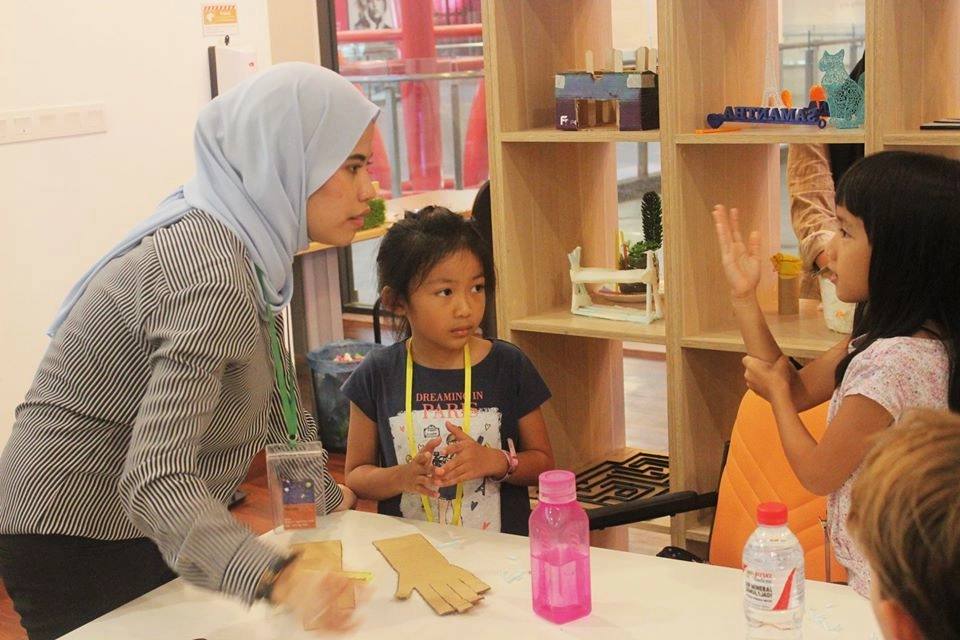 Young children making crafts with a STEM instructor